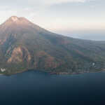 We snorkel on the reef under this volcano on our coral triangle adventures Alor, Indonesia snorkeling tour